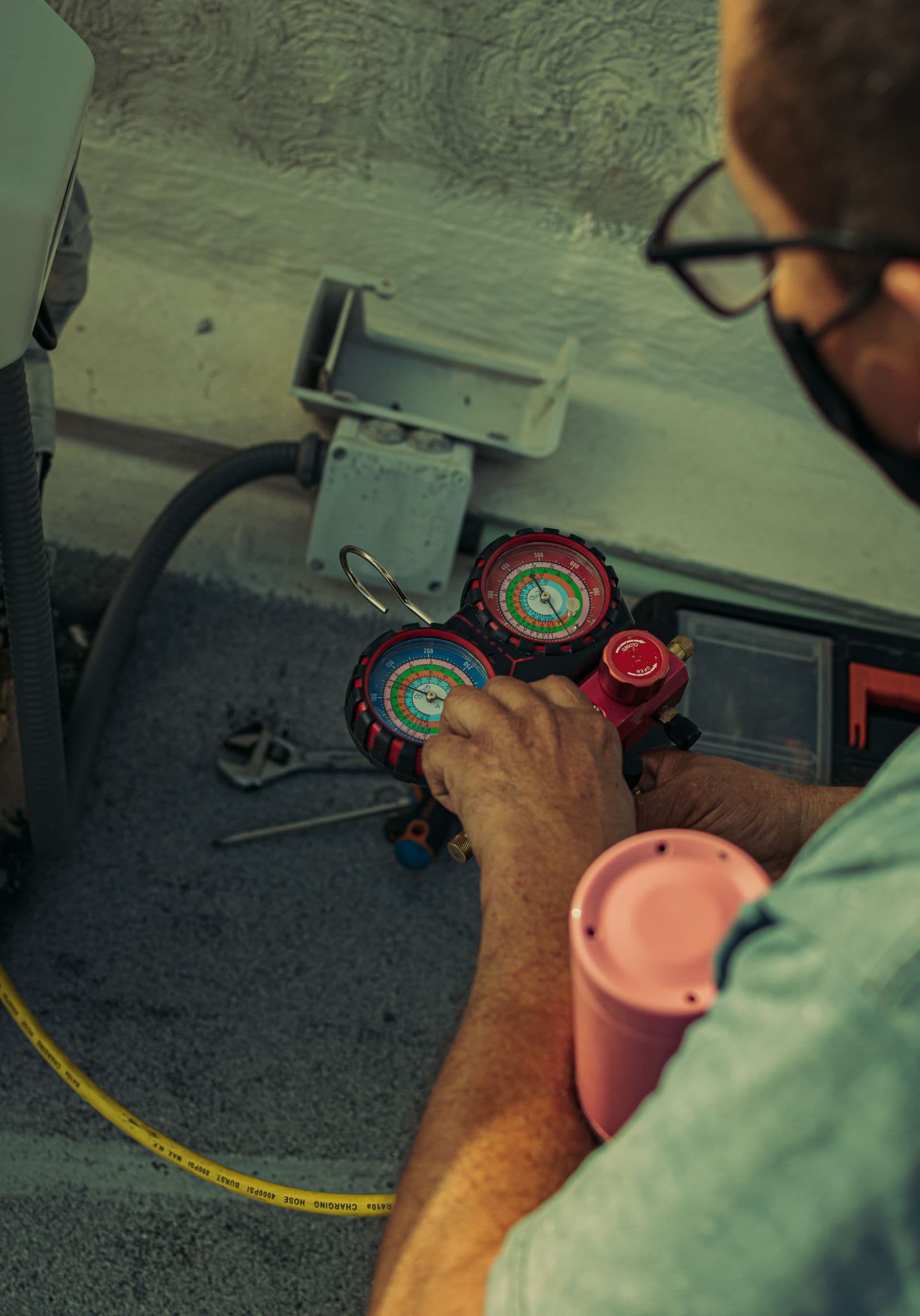 Técnico frigorista a segurar um manifold de pressão durante uma intervenção de recarga numa climatização, ilustrando o controlo F-Gaz do fluido frigorigéneo