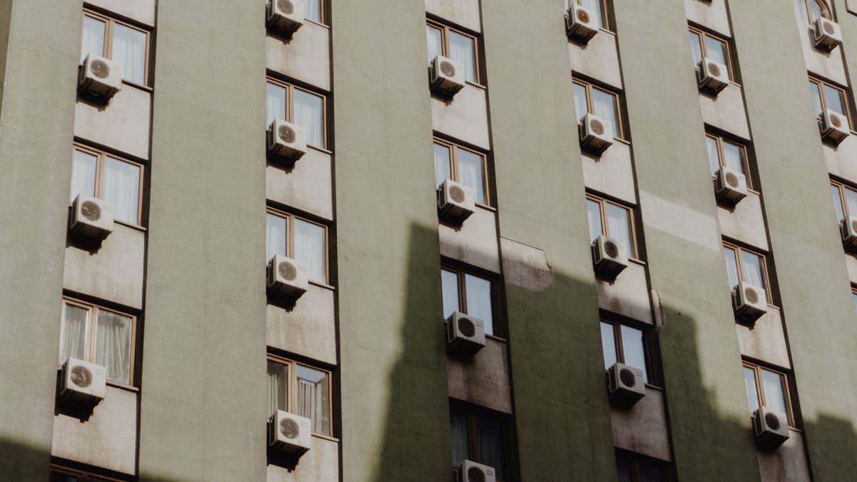 Facciata di un edificio con numerose unità esterne di climatizzazione installate sotto le finestre
