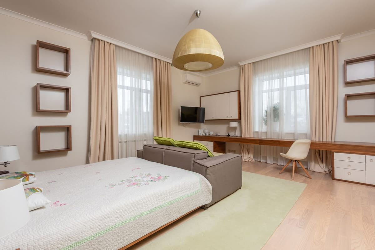 Camera luminosa con unità a parete di climatizzatore reversibile sopra il televisore, letto e scrivania in legno