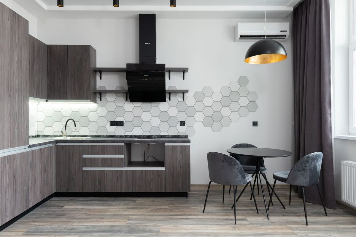 Reversible air conditioning wall unit installed in a modern grey kitchen with a table and chairs
