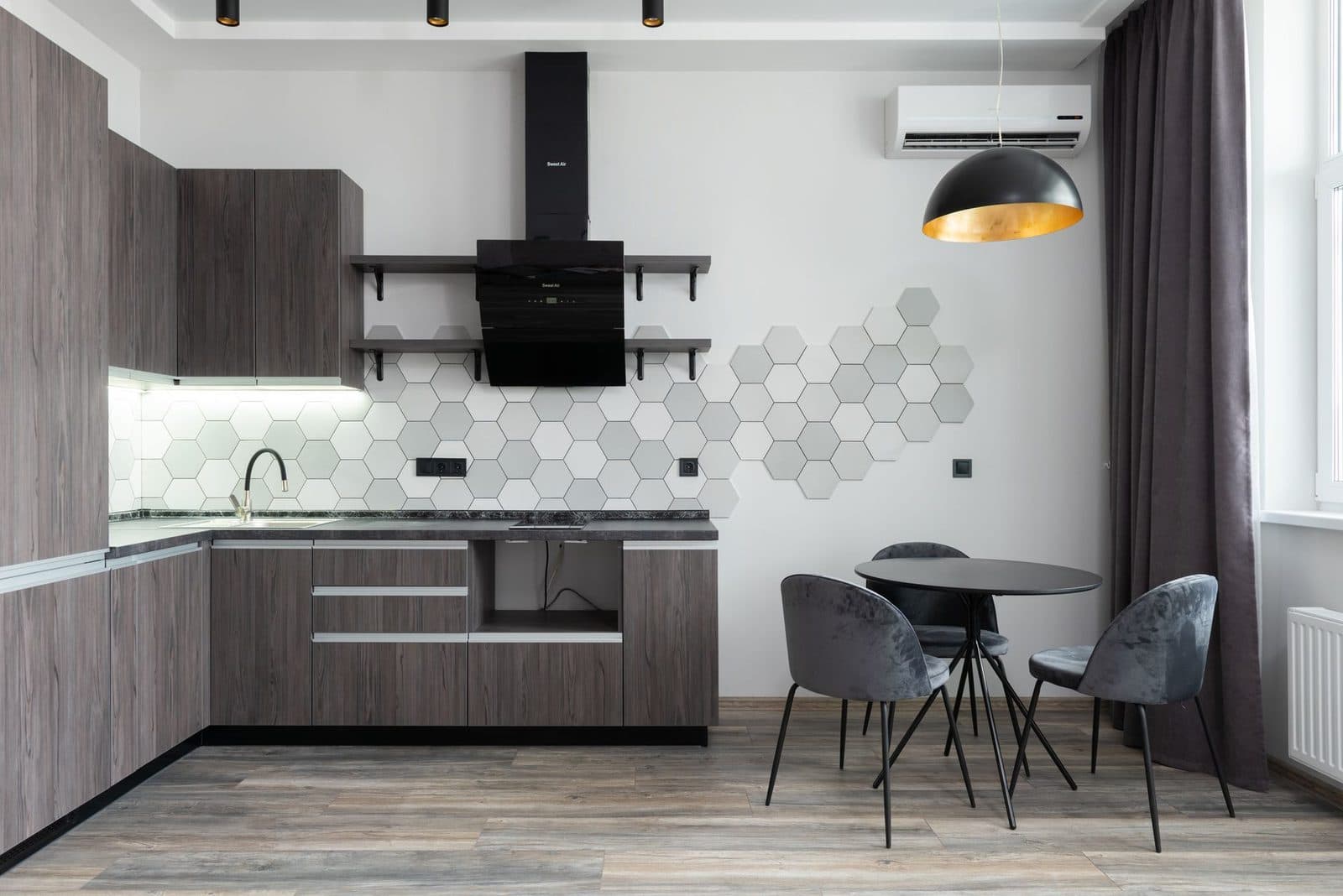 Wandunit van een reversibele airconditioning geïnstalleerd in een moderne grijze keuken met tafel en stoelen