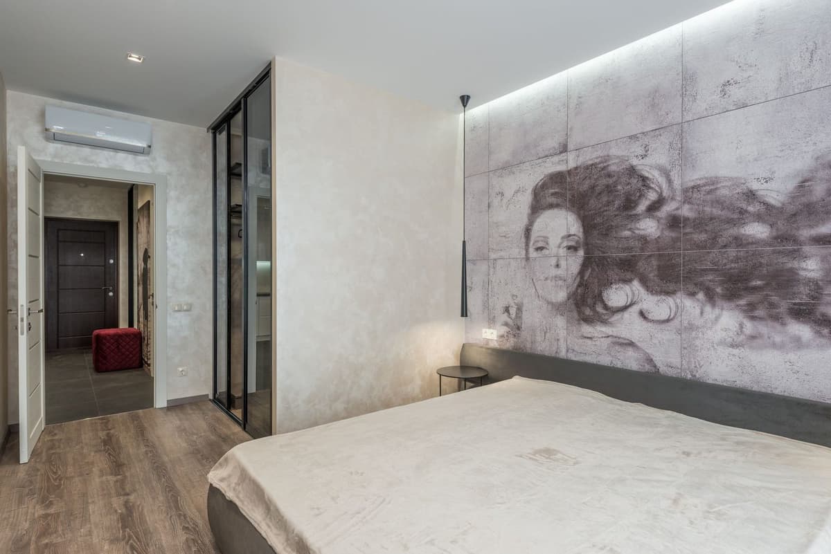 Wandmodel van een omkeerbare airconditioning geïnstalleerd in een moderne slaapkamer met bed en muurschildering