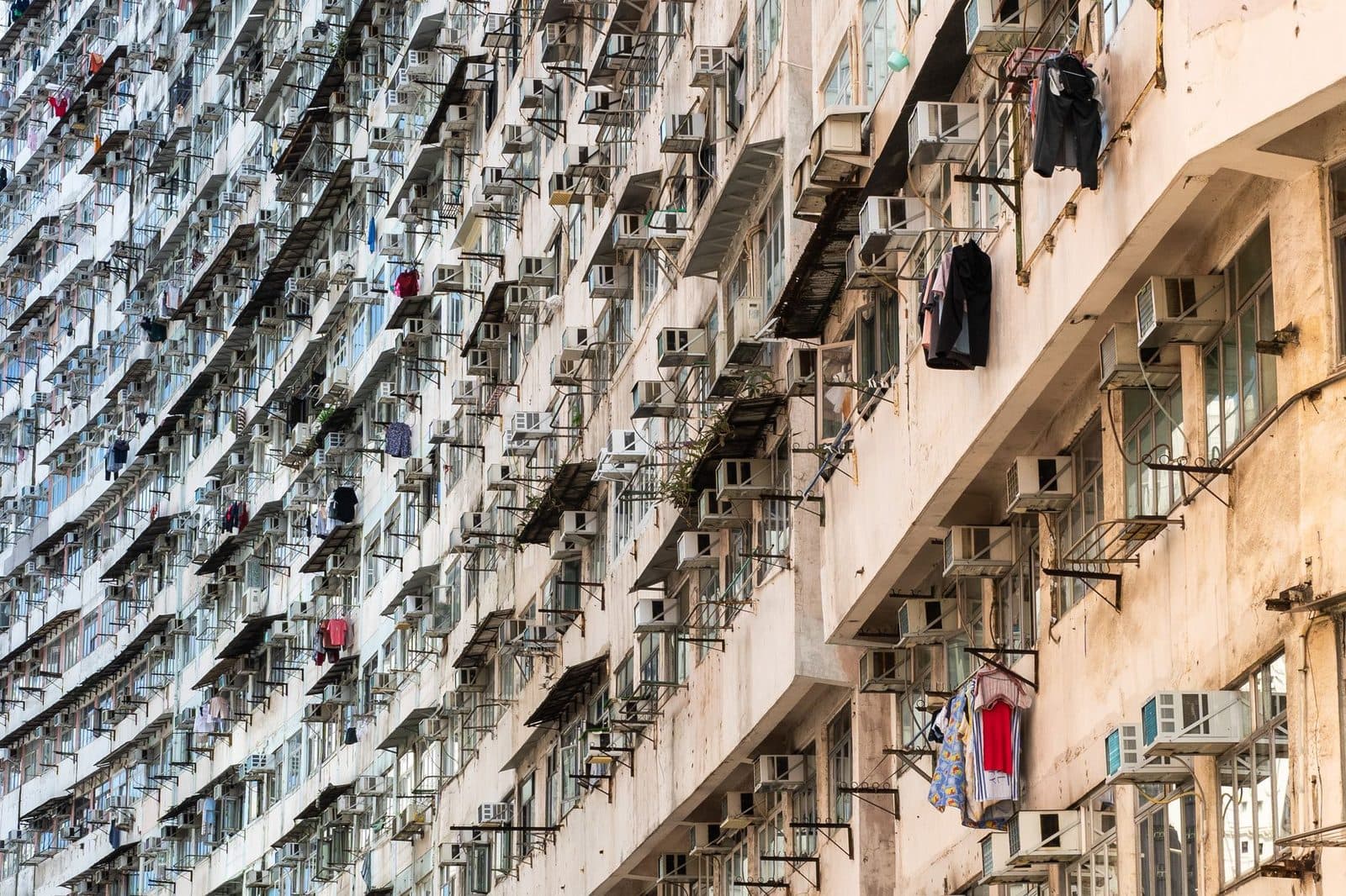 Gevel van een woongebouw vol buitenunits van airconditioners en opgehangen wasgoed