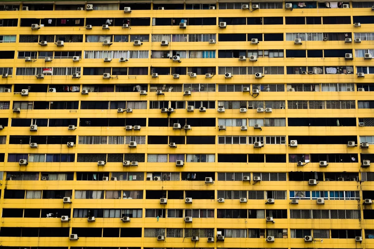 Gelbe Fassade eines Wohnhauses, übersät mit Dutzenden von Klimaanlagen-Außeneinheiten