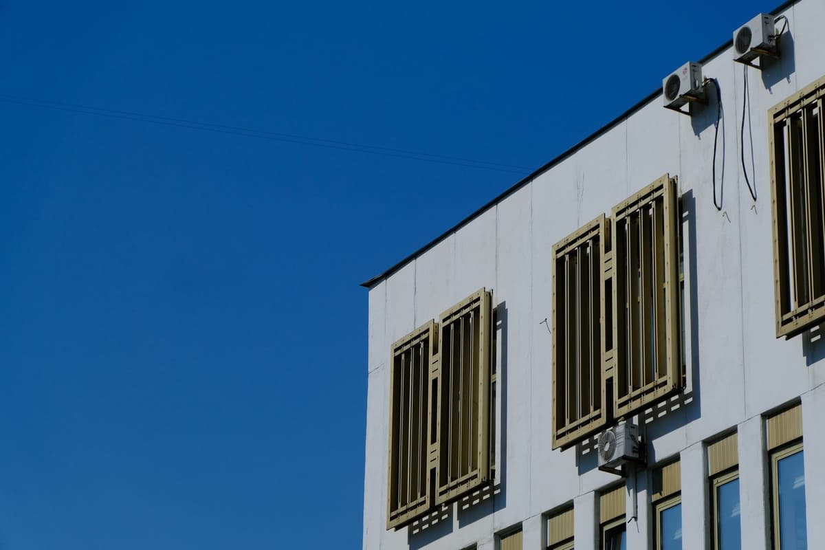 Unità esterne di climatizzazione fissate sulla facciata bianca di un edificio sotto un cielo azzurro