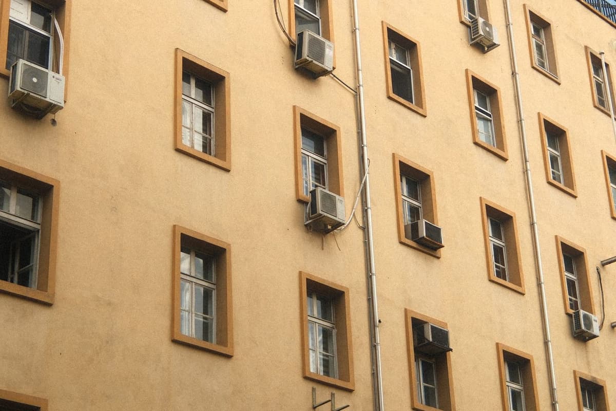 Facciata di un palazzo beige con diversi climatizzatori installati sotto le finestre