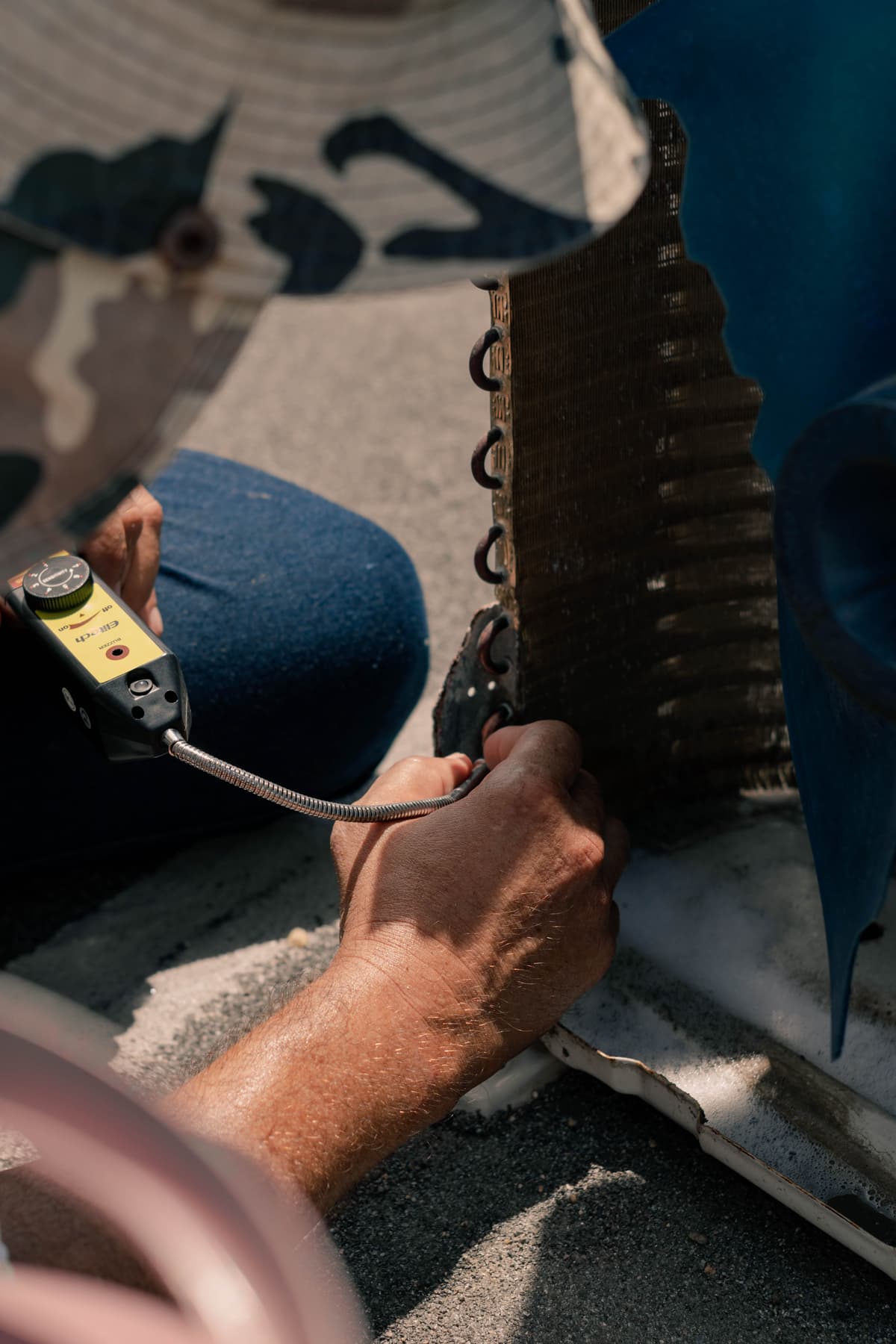 Technicien frigoriste intervenant sur une unité extérieure de climatisation murale avec une mallette d'outils