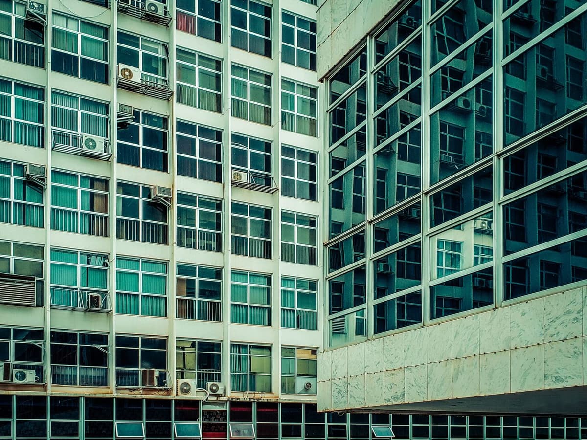 Façade d'un bâtiment moderne avec plusieurs unités de pompes à chaleur air-air installées aux fenêtres.