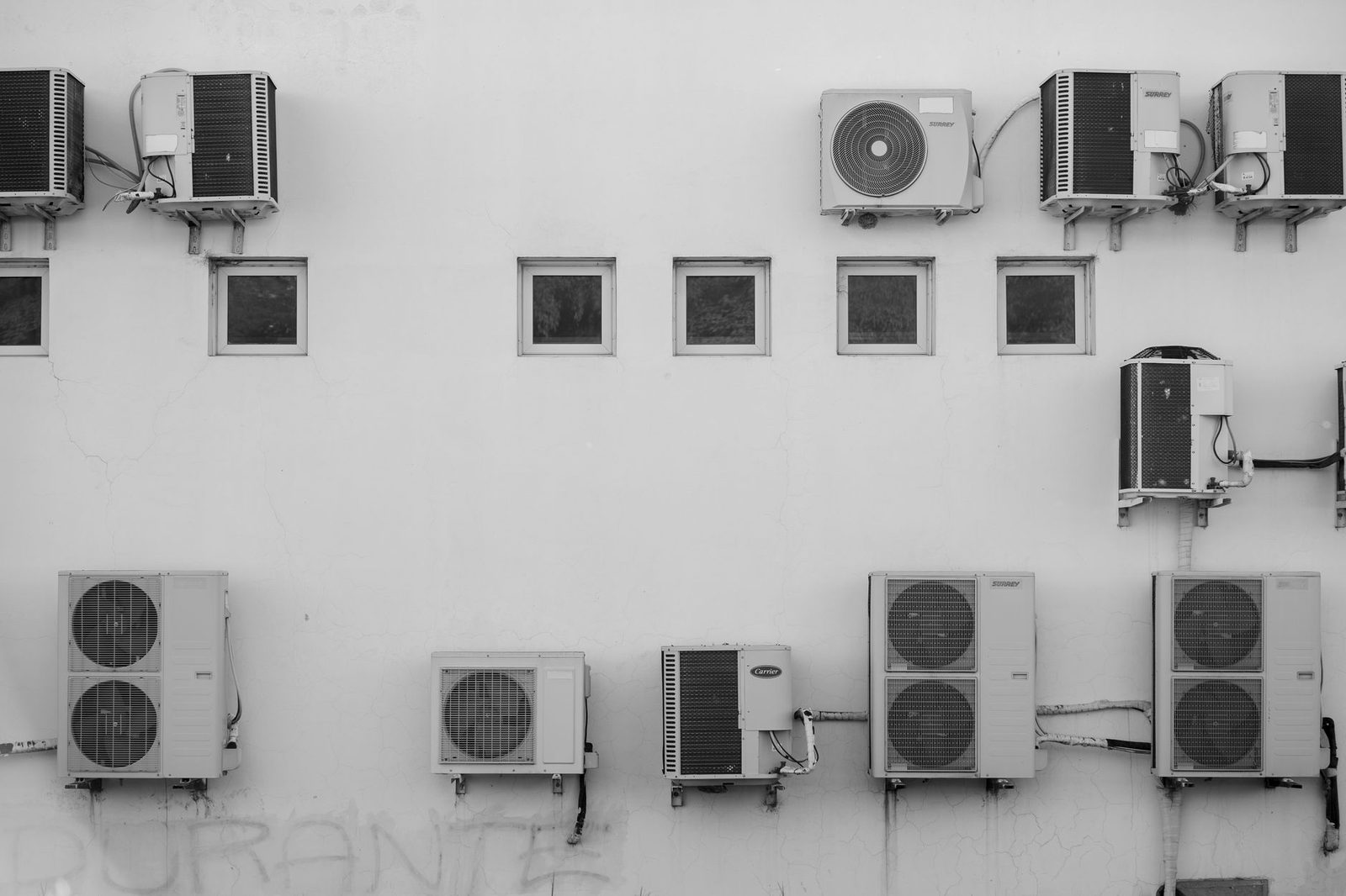 Unités extérieures de climatiseurs fixées sur un mur blanc, photo en noir et blanc