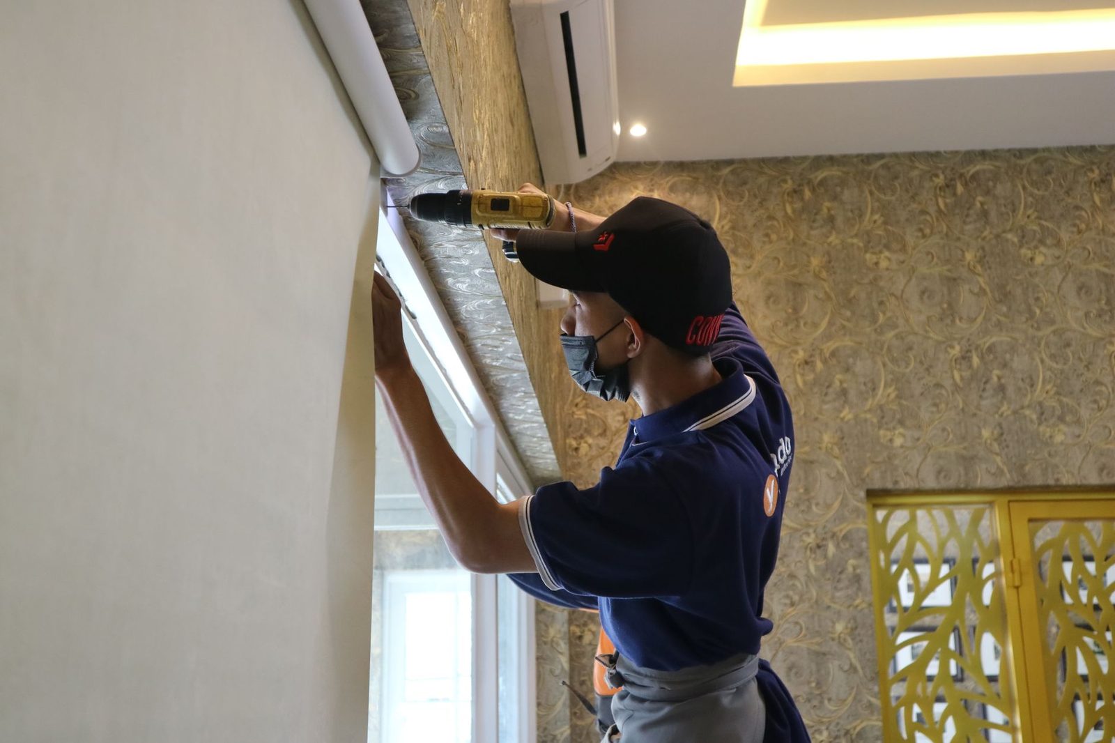 Technician drilling a wall to install an indoor wall-mounted air conditioning unit