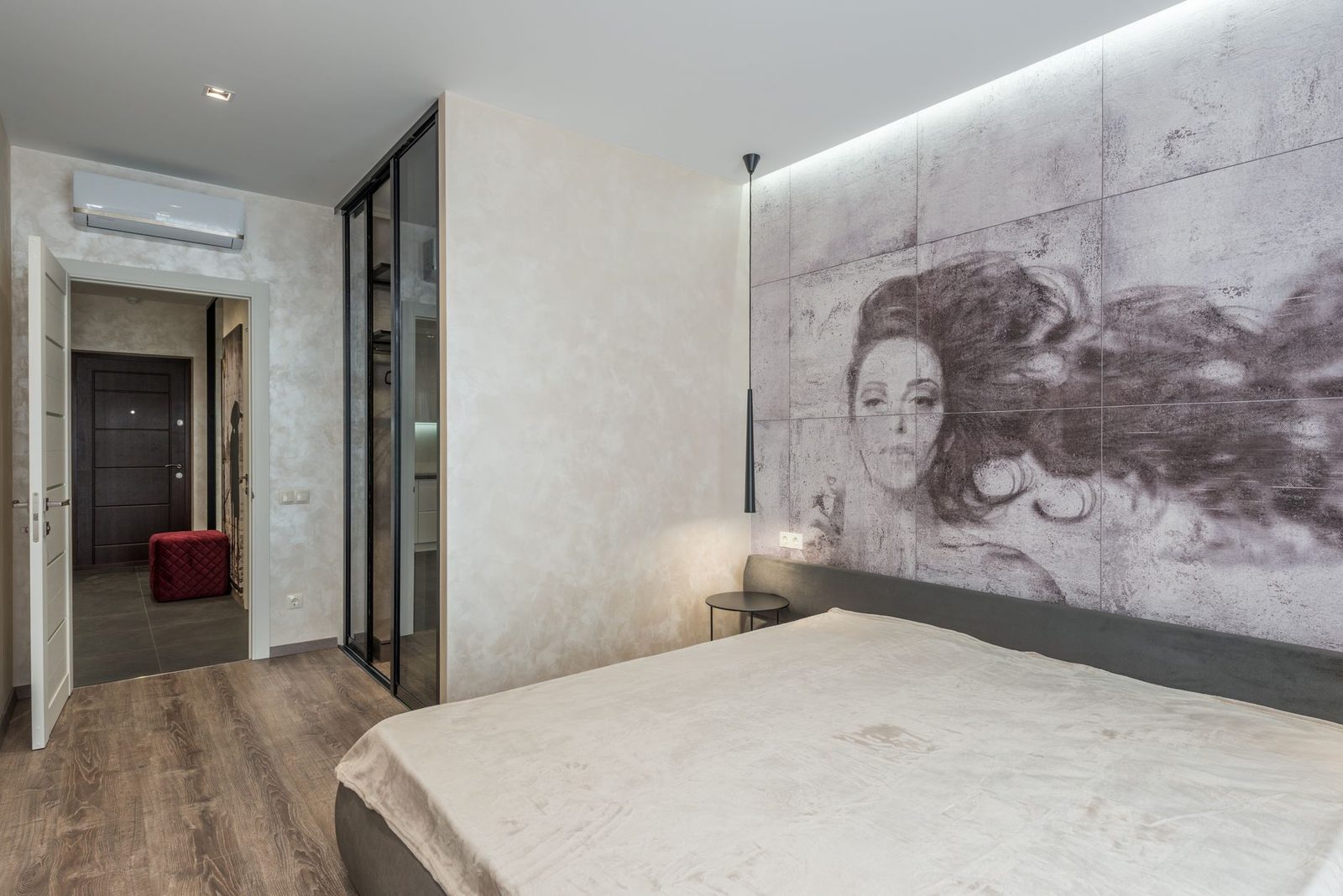 Unidade mural de ar condicionado reversível instalada num quarto moderno com cama e mural pintado na parede