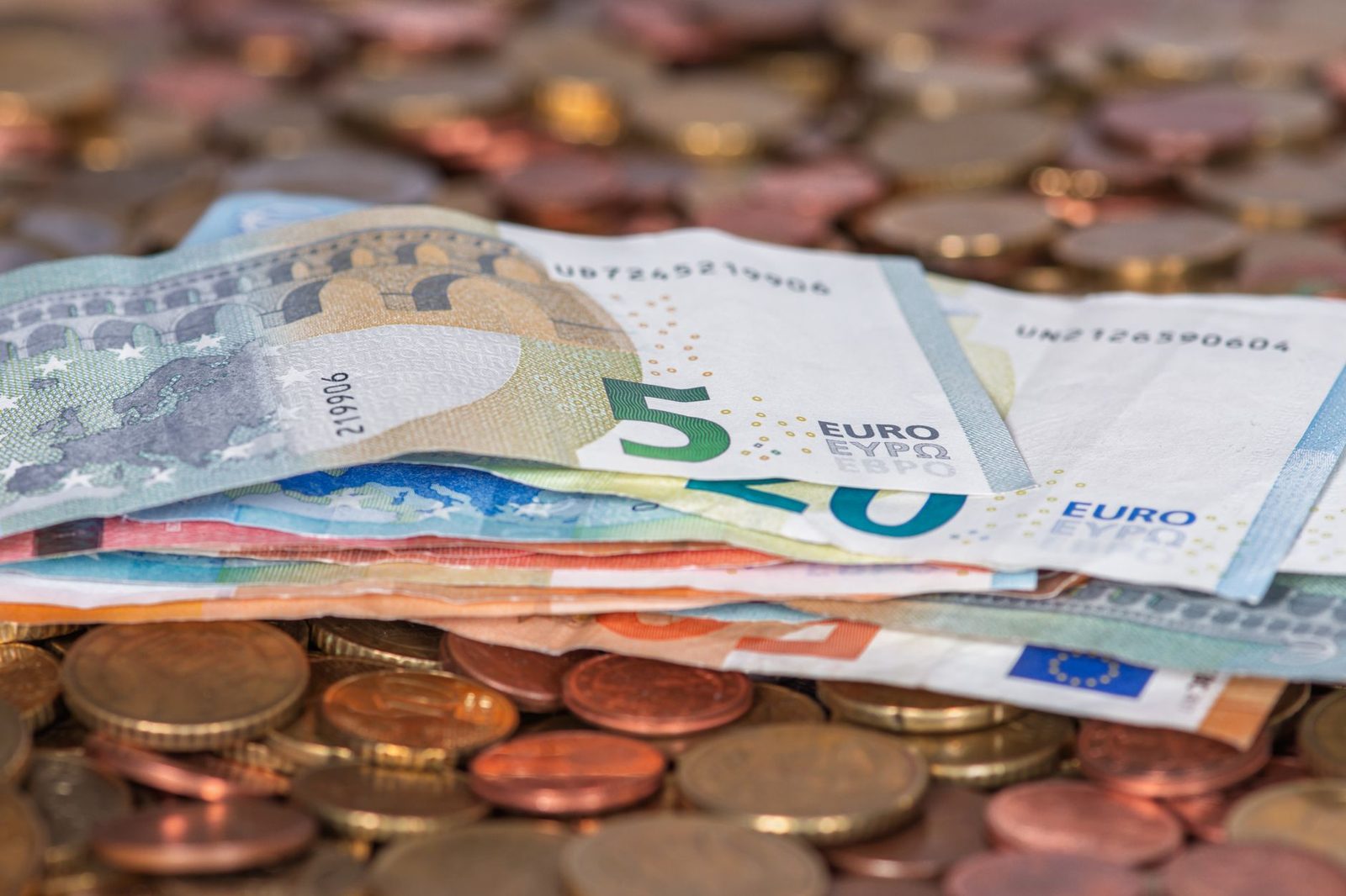 Bündel Euro-Geldscheine auf einem Haufen Münzen