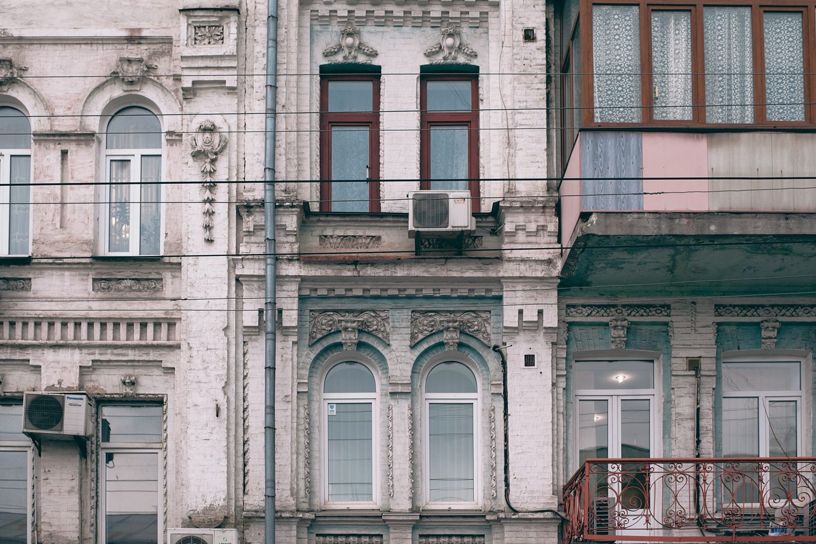 Unités extérieures de climatisation fixées sur la façade ancienne d'un immeuble aux fenêtres cintrées