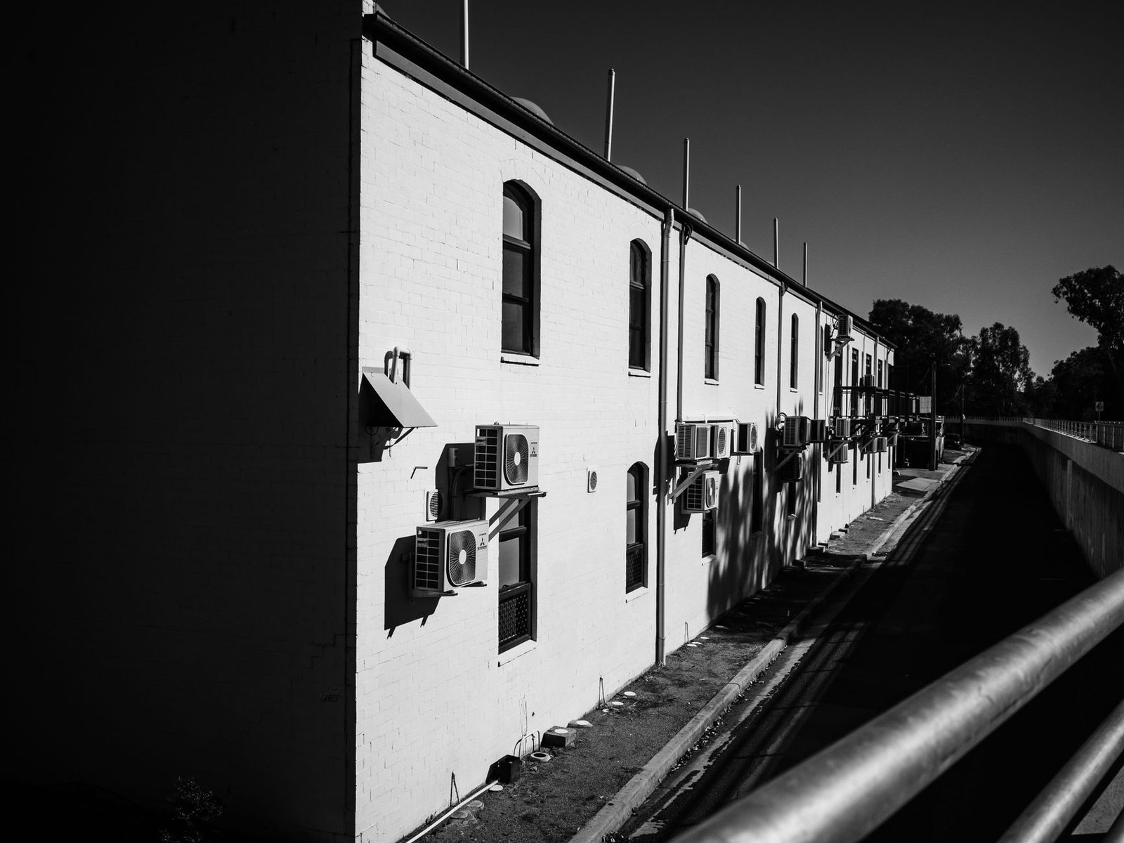 Unités extérieures de climatisation fixées sur la façade blanche d'un bâtiment, photo en noir et blanc