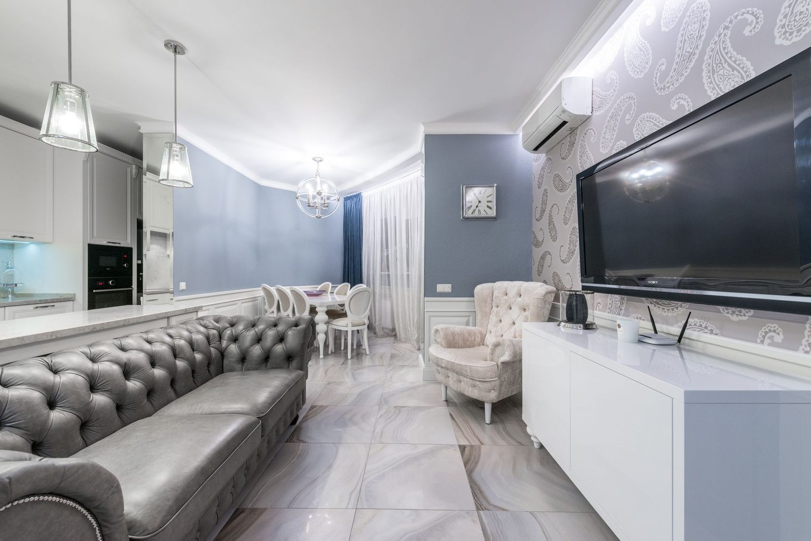 Aire acondicionado de pared instalado encima de un televisor en un salón-comedor moderno en tonos grises