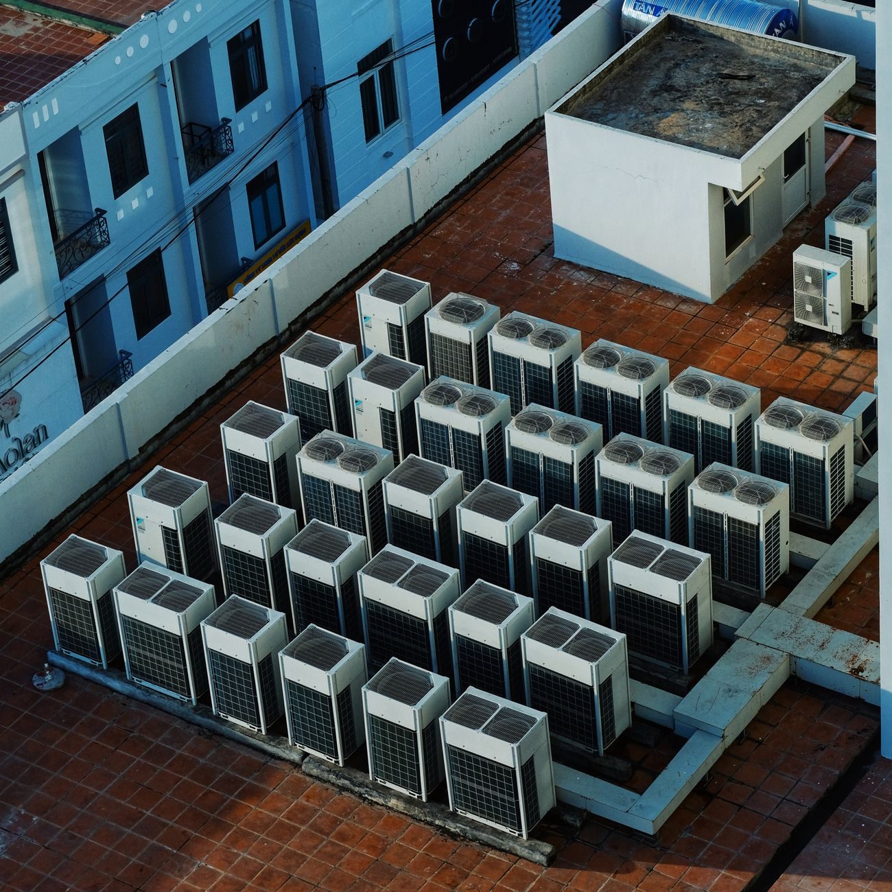 Tientallen buitenunits van airconditioning op een rij op het betegelde dak van een gebouw