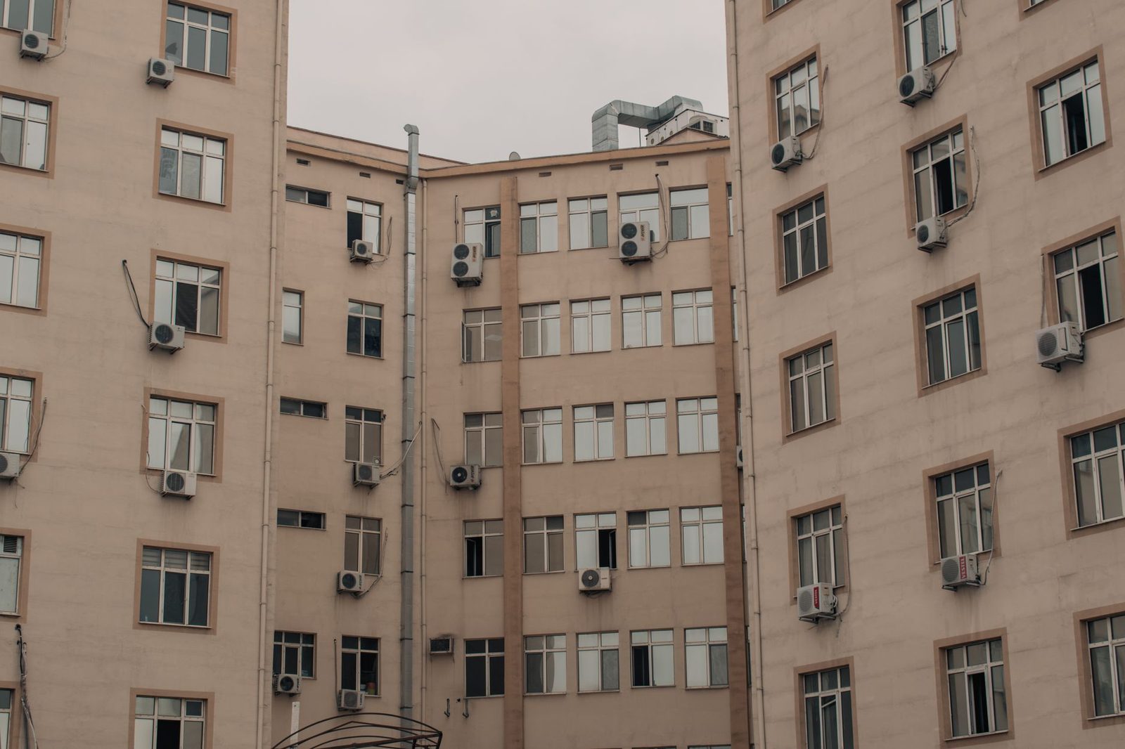 Wohnhausfassade voller Klimaanlagen-Außeneinheiten, die unter den Fenstern montiert sind
