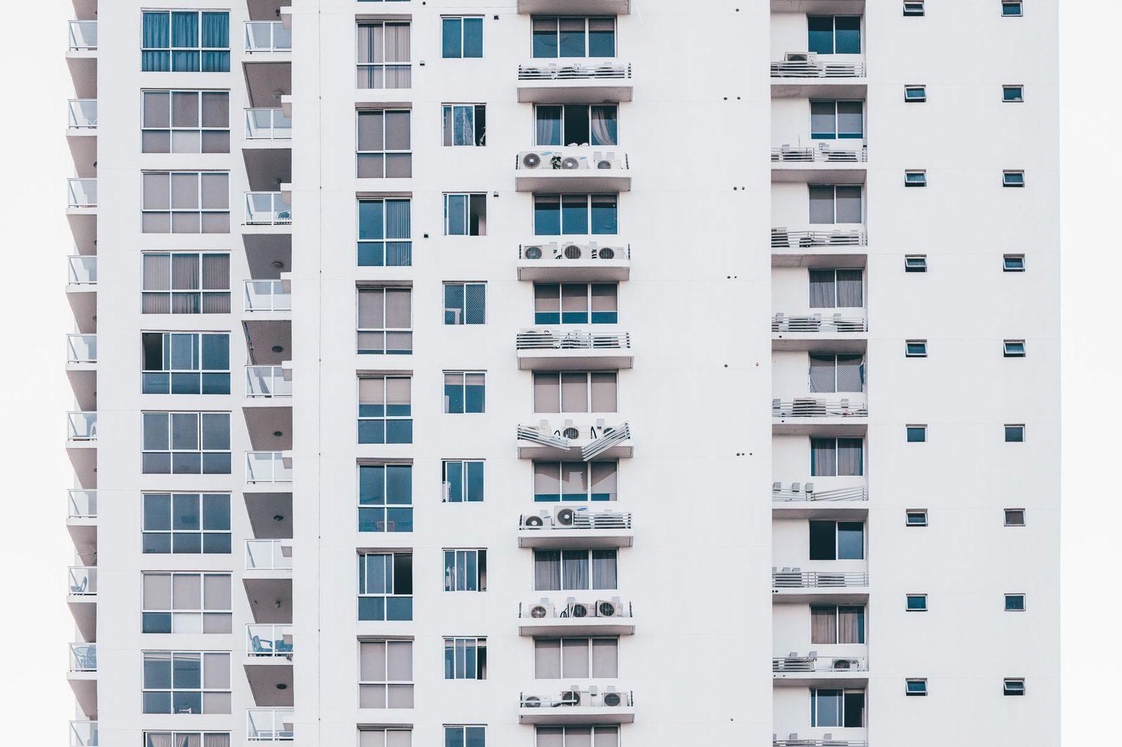 Façade d'immeuble blanc avec unités extérieures de climatisation installées sur les balcons