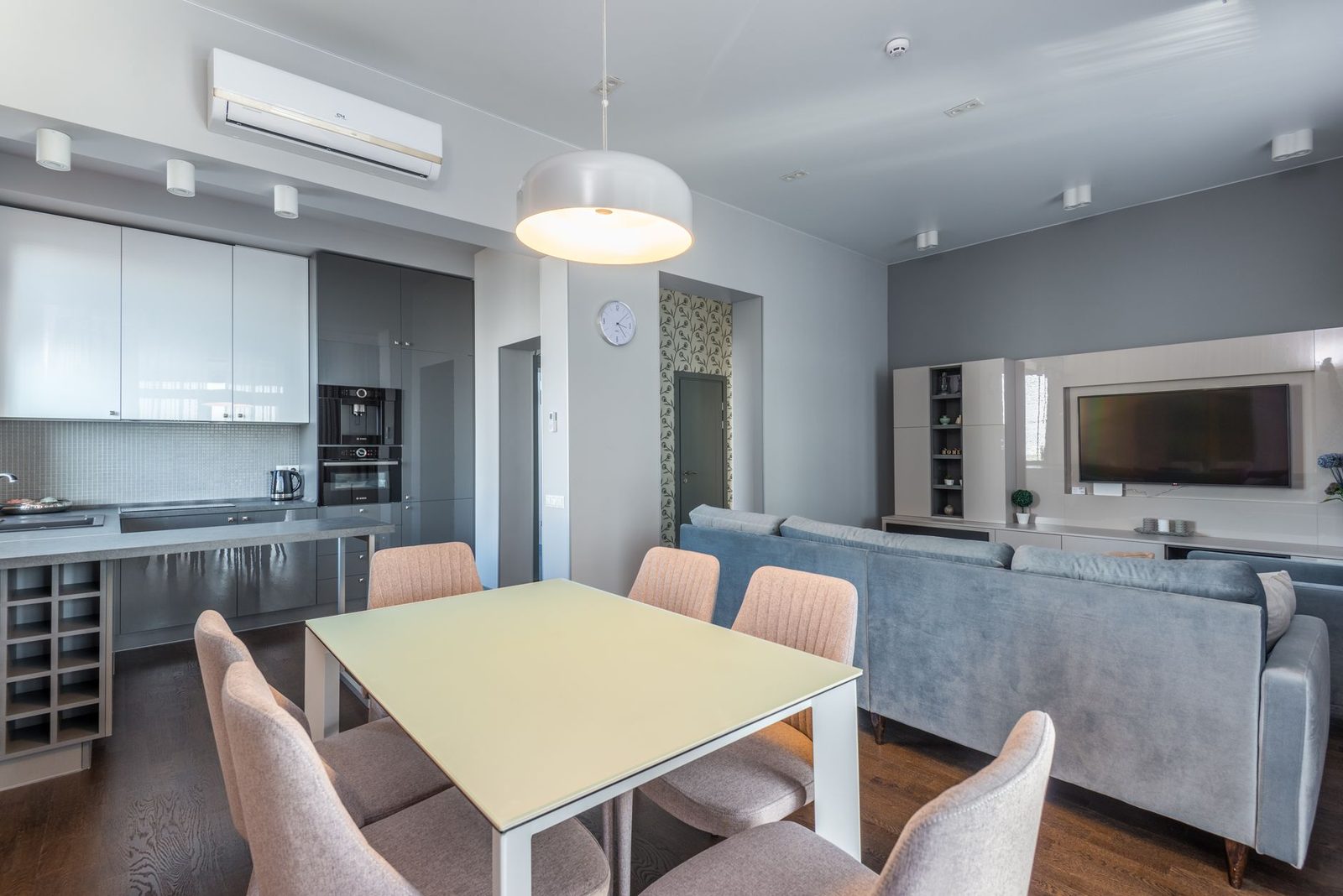 Witte wandairco hoog geplaatst in een moderne woonkeuken met tafel en bank