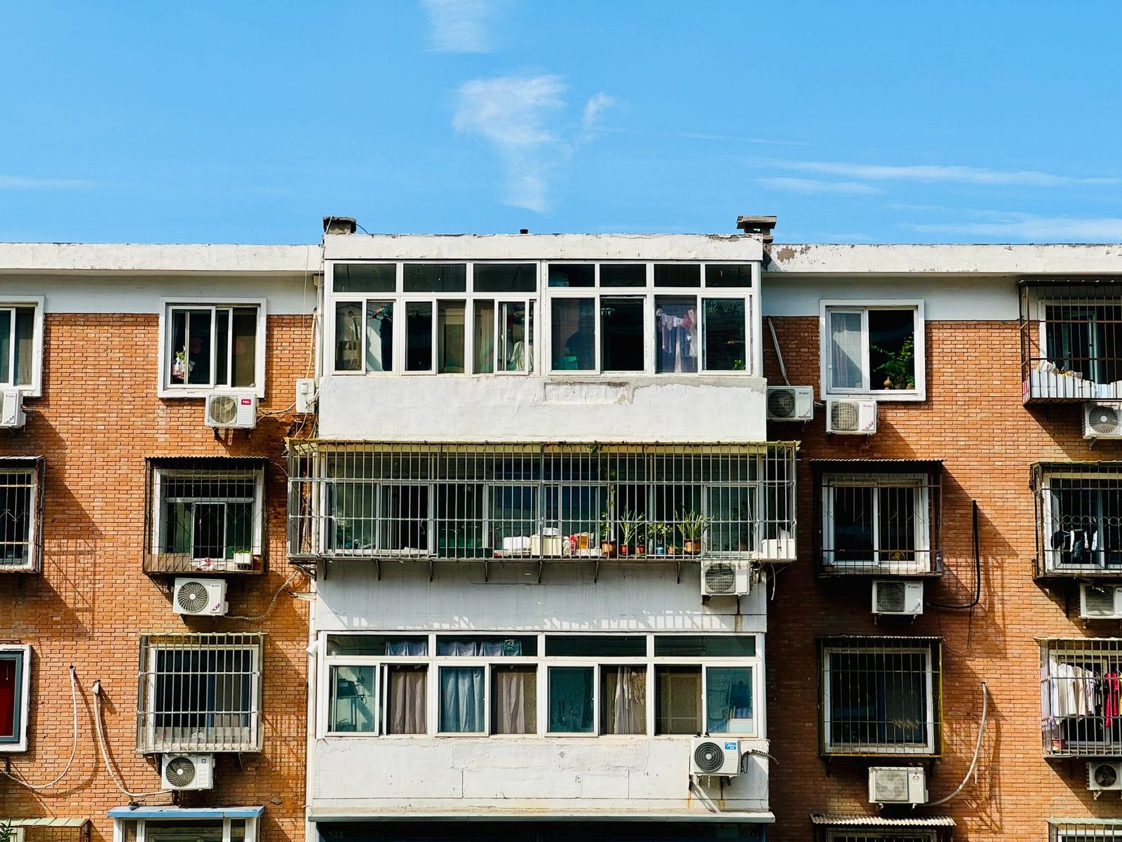 Façade d'immeuble en briques avec de nombreux groupes extérieurs de climatiseurs fixés sous les fenêtres