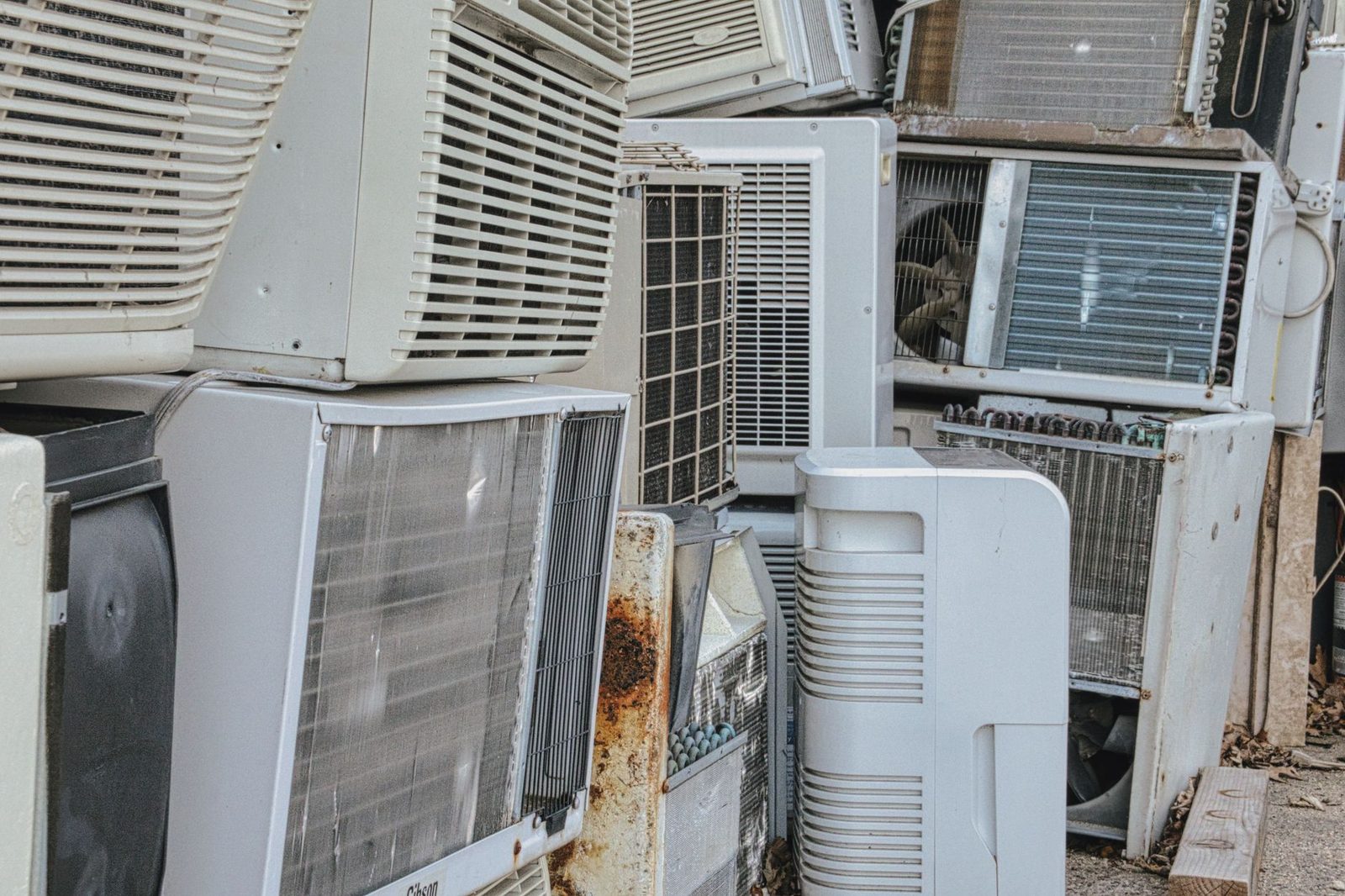 Amas de vieux climatiseurs et unités extérieures usagés empilés en plein air dans une casse
