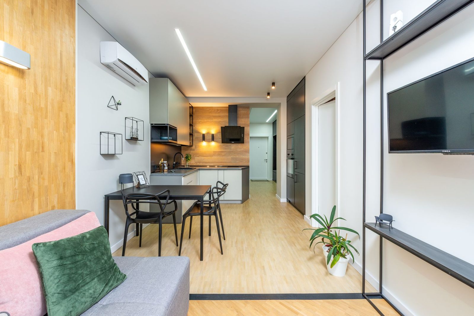 Climatizzatore a parete installato in un salotto moderno con cucina a vista, tavolo da pranzo e parquet chiaro