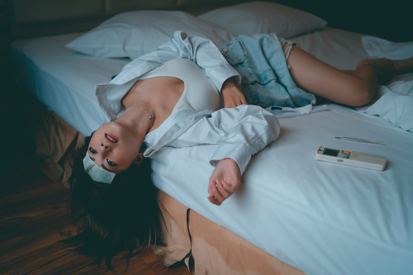 Jeune femme allongée sur un lit avec une télécommande de climatisation posée à côté d'elle