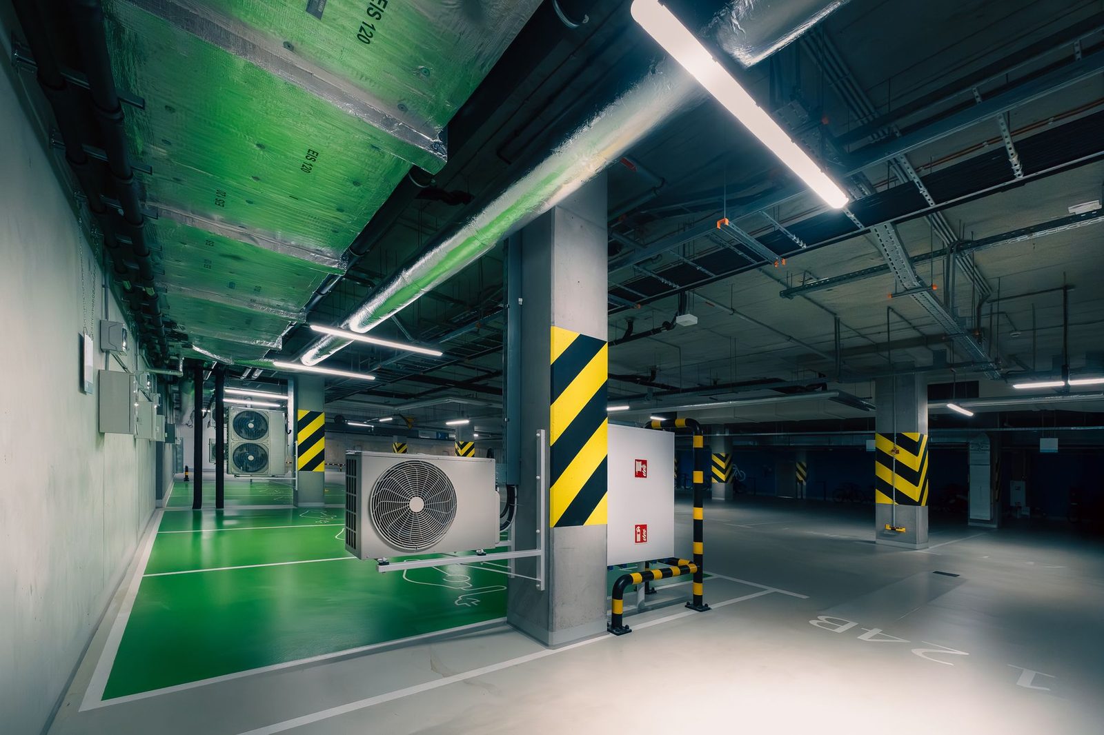 Outdoor units of air-to-air heat pumps installed in a lit underground car park