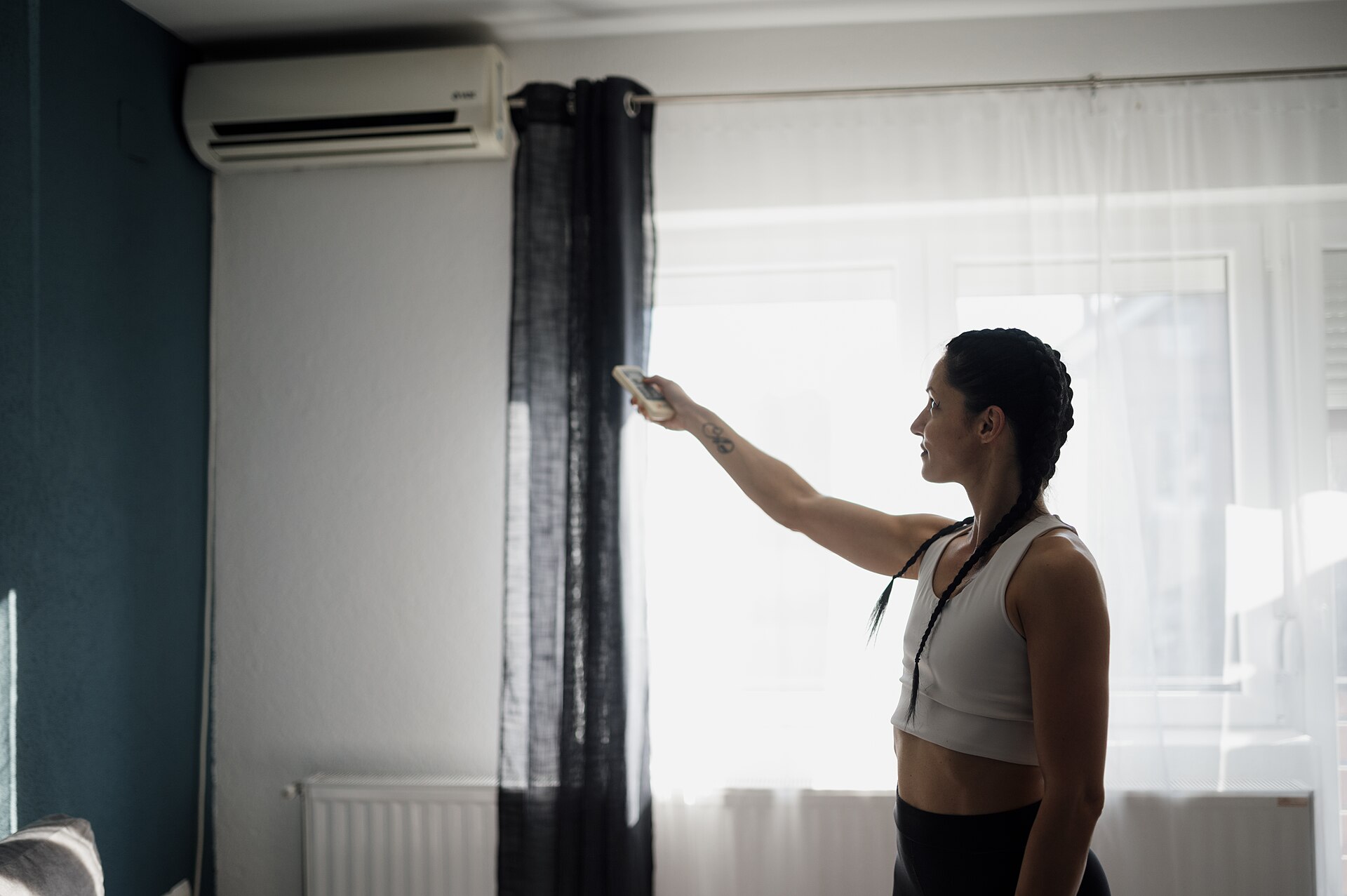 Person, die eine Klimaanlage in einem Wohnzimmer einstellt